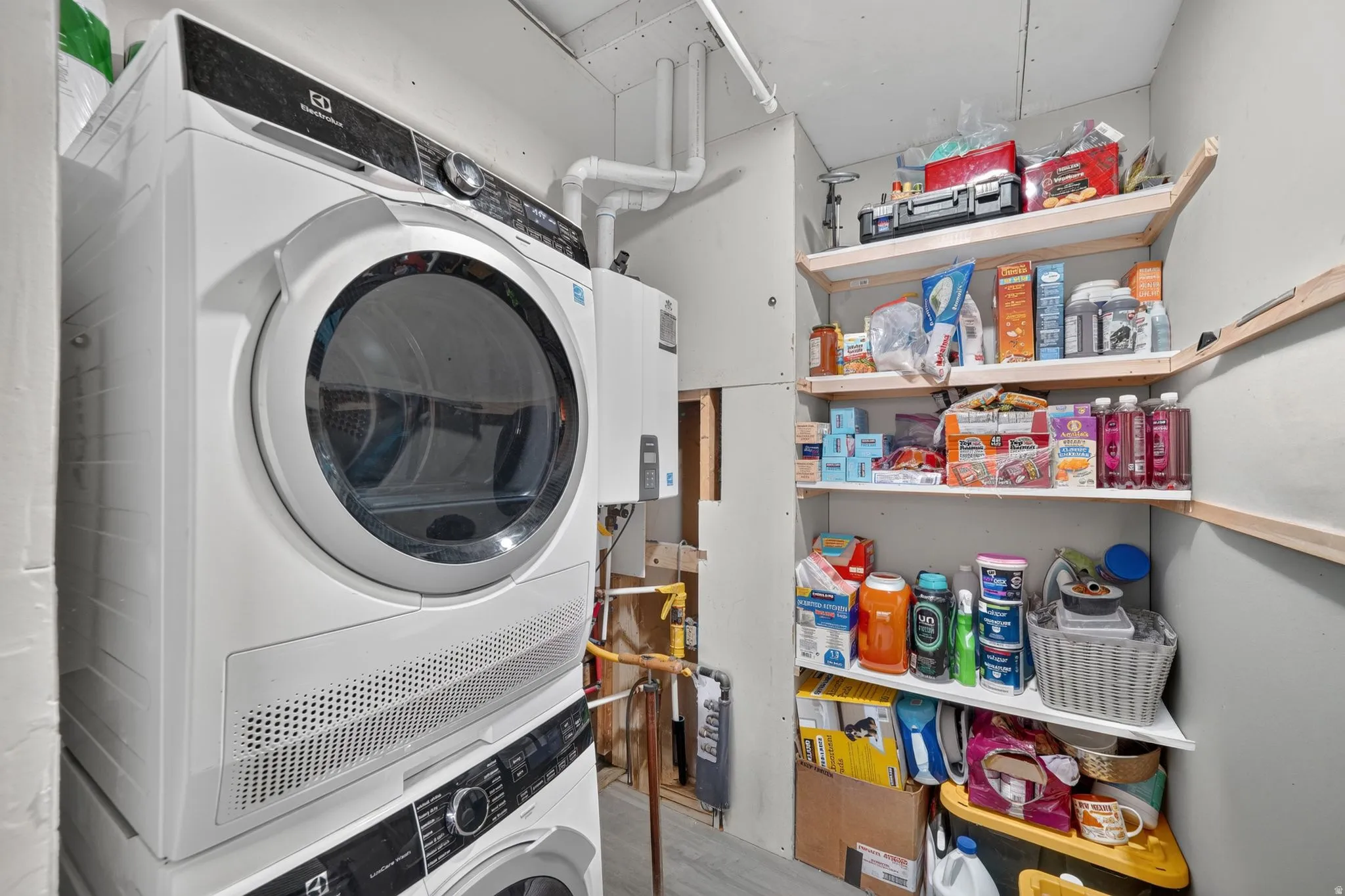 Stackable laundry appliances with a front-loading design, wall-mounted water heater, and built-in corner shelving