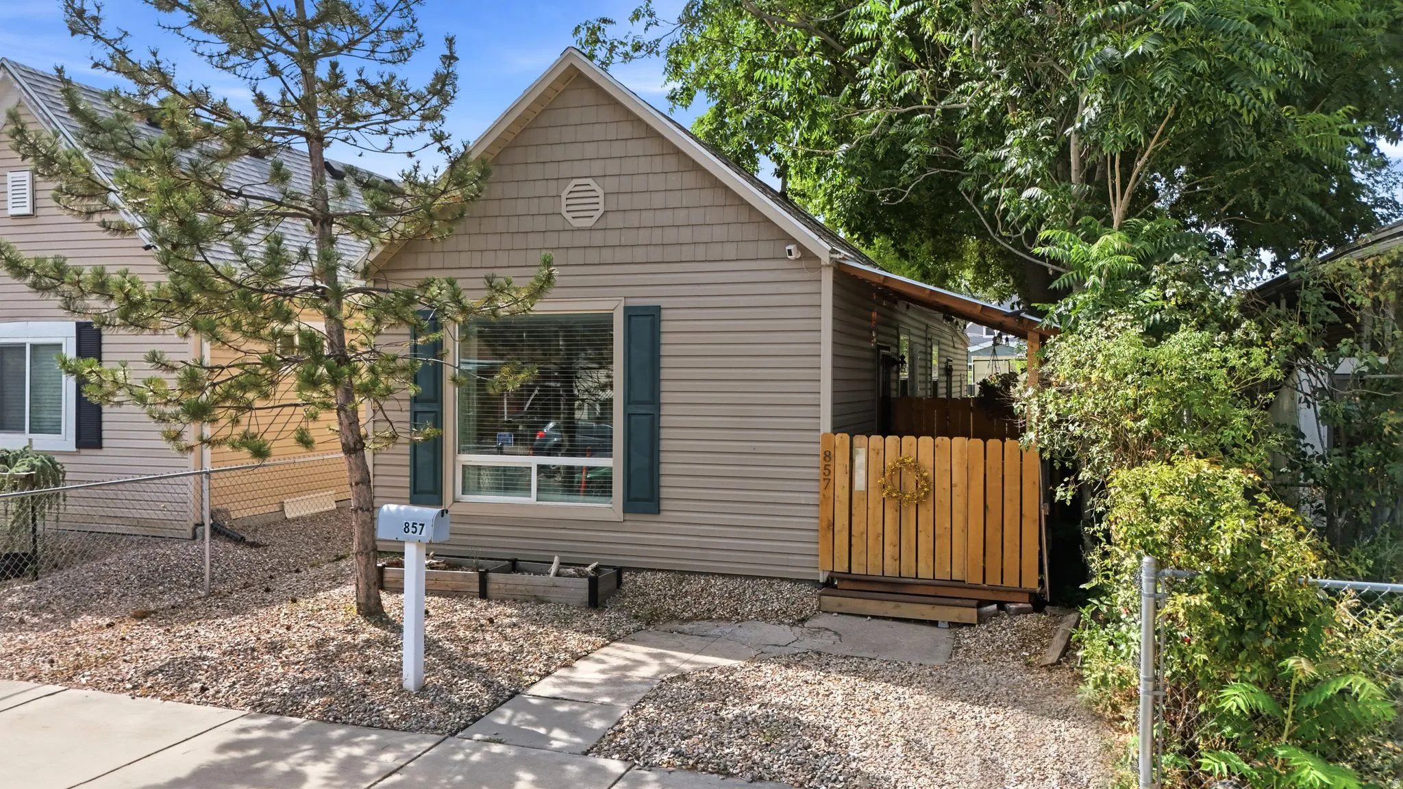 Fiber cement siding exterior with a pitched roof, decorative gable vent, large front window, and a wood privacy fence