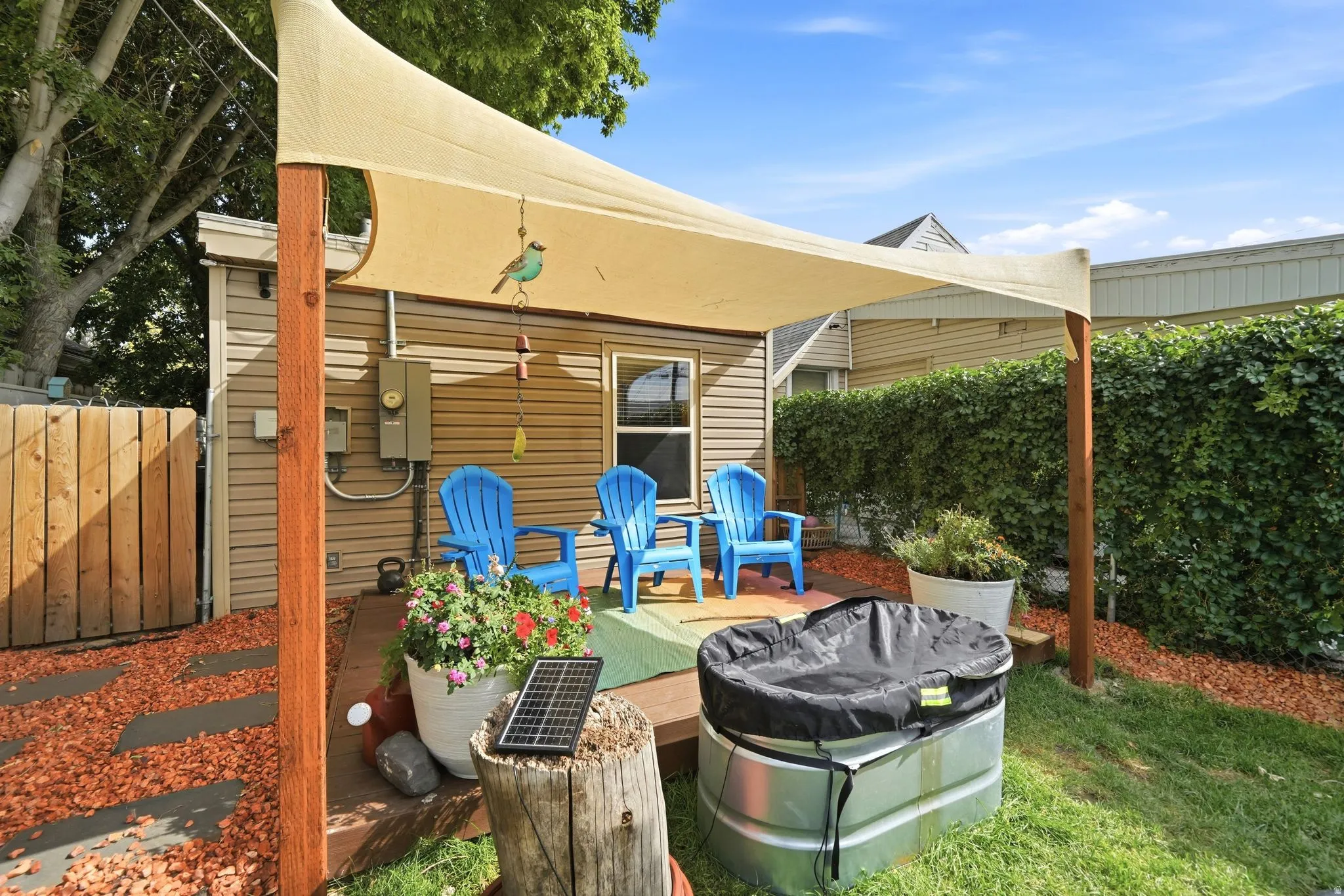 Patio with a tensile fabric shade structure, wood-plank decking, and a privacy fence