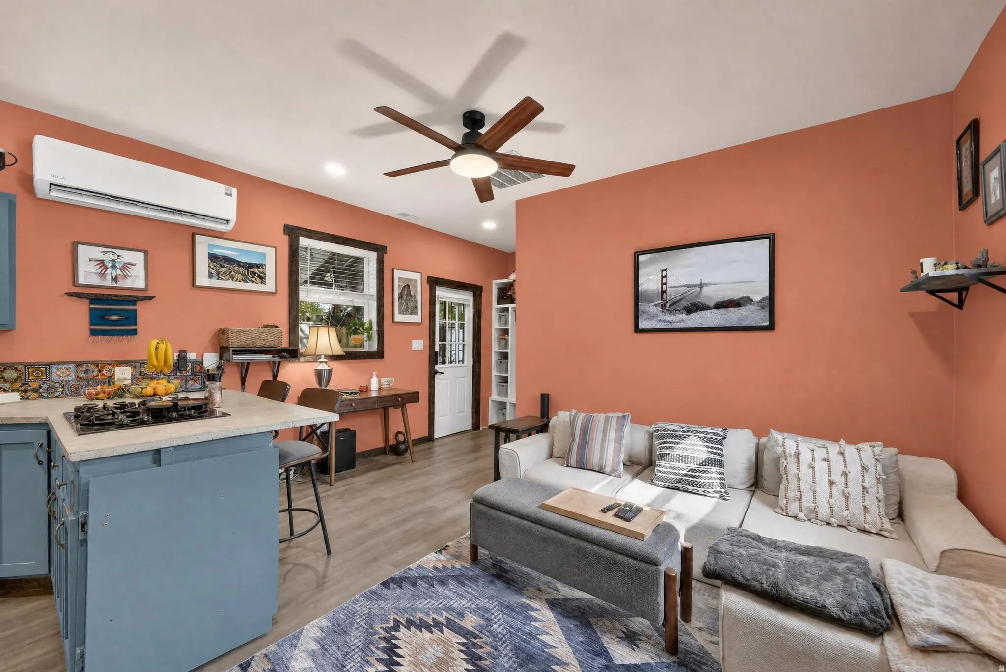 Built-in kitchen island with integrated cooktop, wood-finish flooring, recessed lighting, and a ceiling fan with integrated lighting