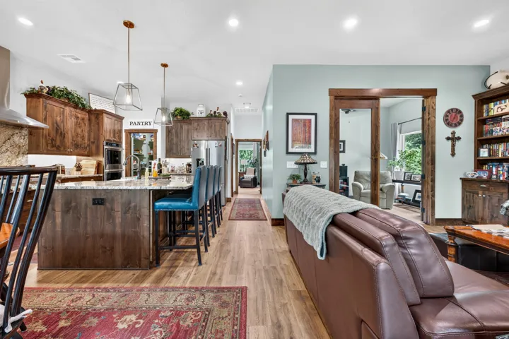 Open-concept kitchen with wood-finish flooring, recessed lighting, double ovens, and a large central island with seating