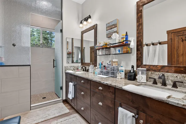 Dual vanity with granite countertops, rich wood cabinetry, and oil-rubbed bronze fixtures