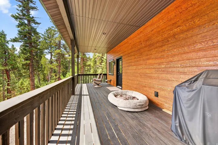 Expansive covered deck featuring wood decking, a durable wood railing, and a tongue and groove ceiling