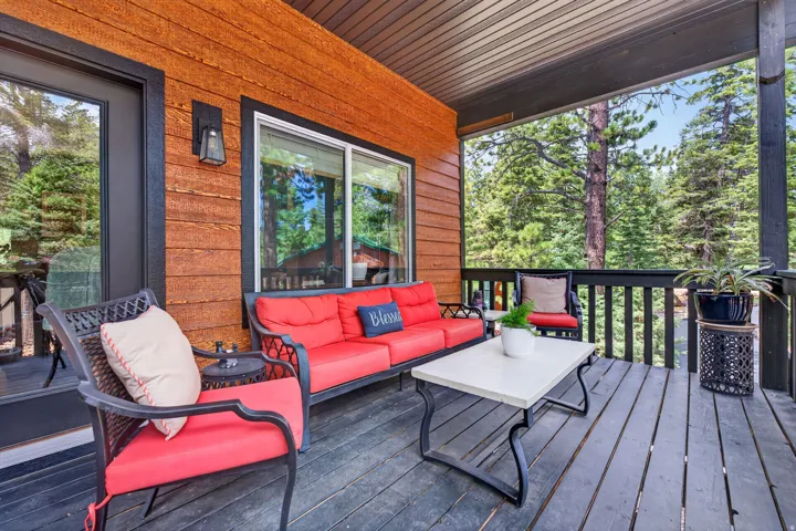 Covered deck featuring wood-finish siding, black railings, and an exterior wall sconce