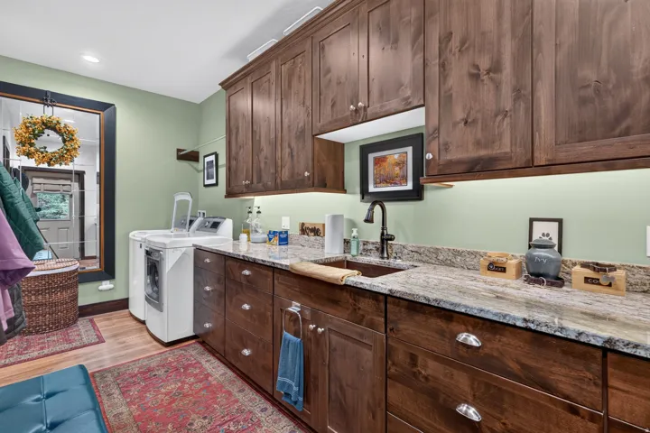 Extensive wood-finish cabinetry, under-cabinet lighting, and a utility sink with a black-finish faucet complement the durable countertop