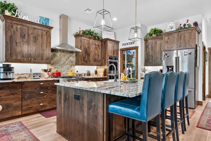 Wood cabinetry with granite countertops, stainless steel appliances, a center island with bar seating, and a walk-in pantry