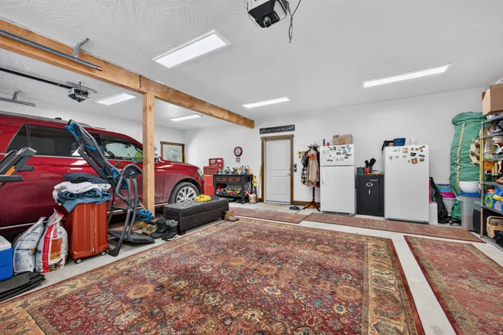 Overhead garage door system, exposed wood beam, recessed lighting, white interior door, and white walls
