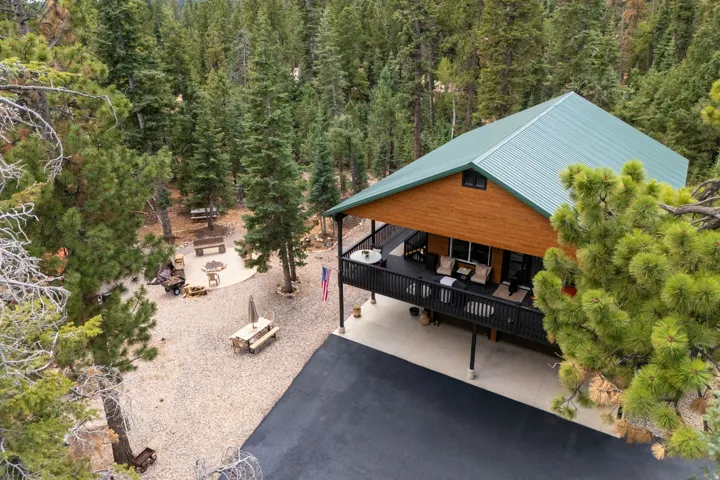 Wood-sided structure featuring a green metal roof, elevated deck, and paved driveway