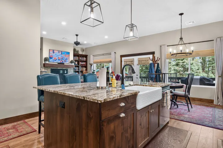 Open-concept kitchen and dining area featuring a dark wood island with granite countertop, stainless steel appliances, and pendant lighting