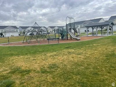 Community greenspace featuring a playground, climbing structure, and covered picnic area
