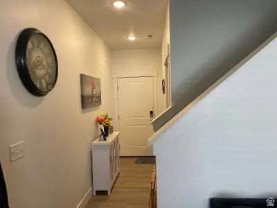Welcoming entryway featuring hardwood flooring, recessed ceiling lighting, and a round wall clock