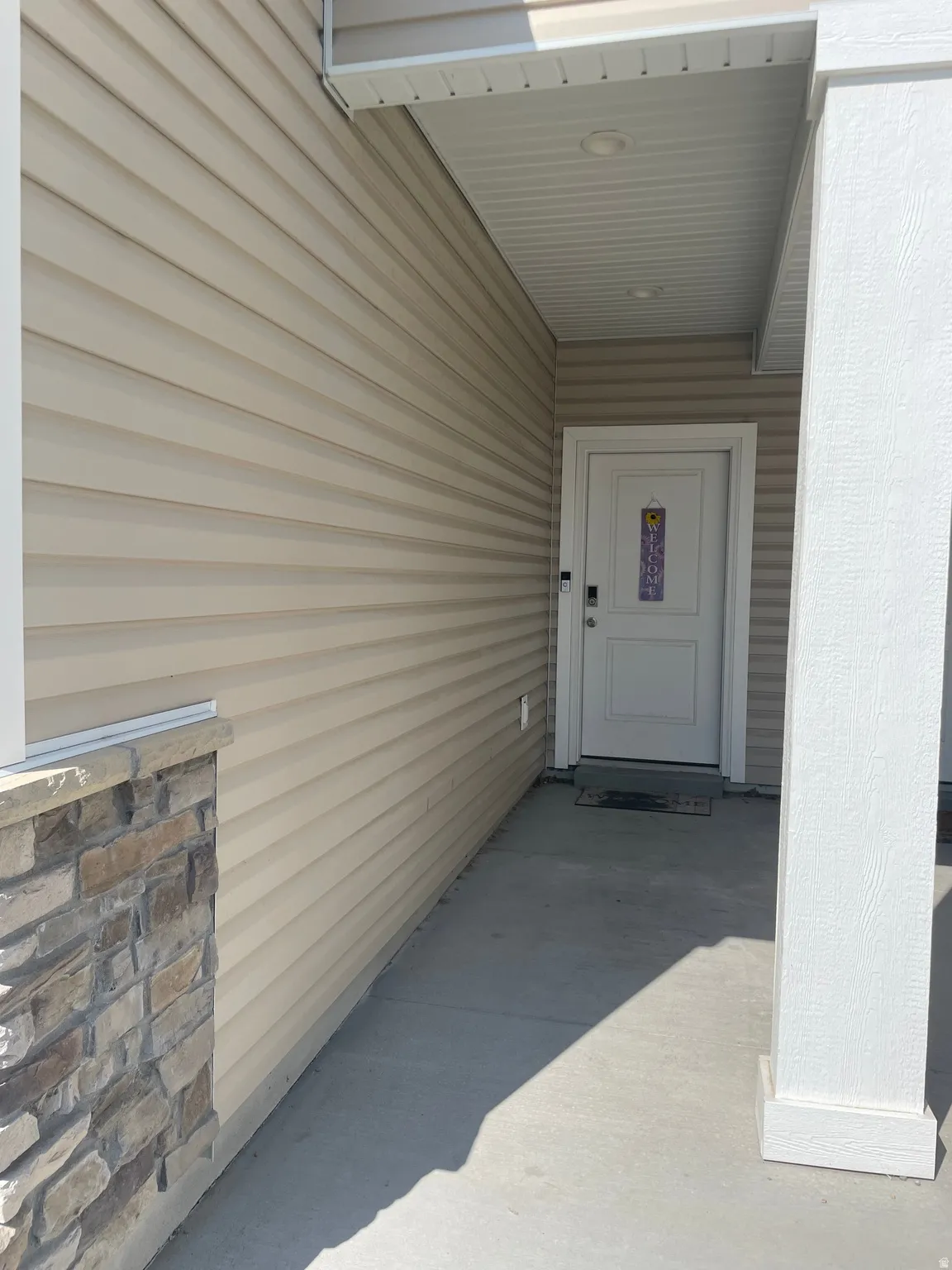 Entryway featuring horizontal siding, stone veneer accents, and a covered porch with recessed lighting