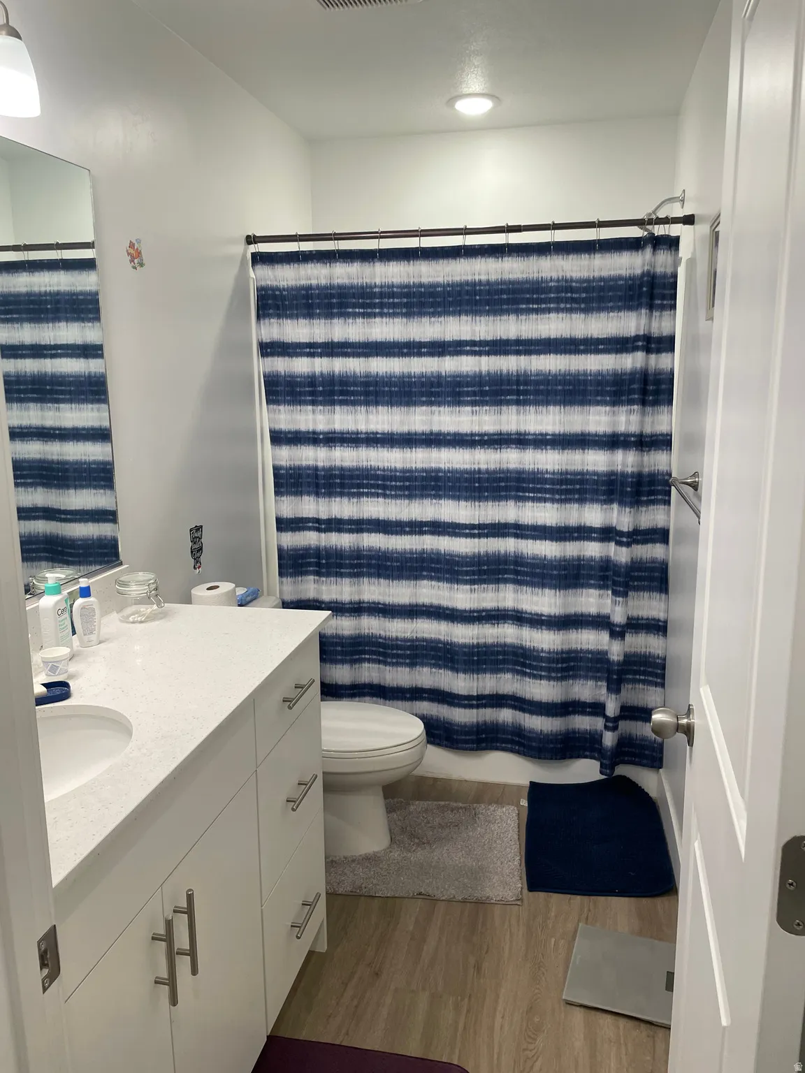 Bright, updated bathroom featuring a white vanity with ample storage, porcelain sink, and chrome fixtures