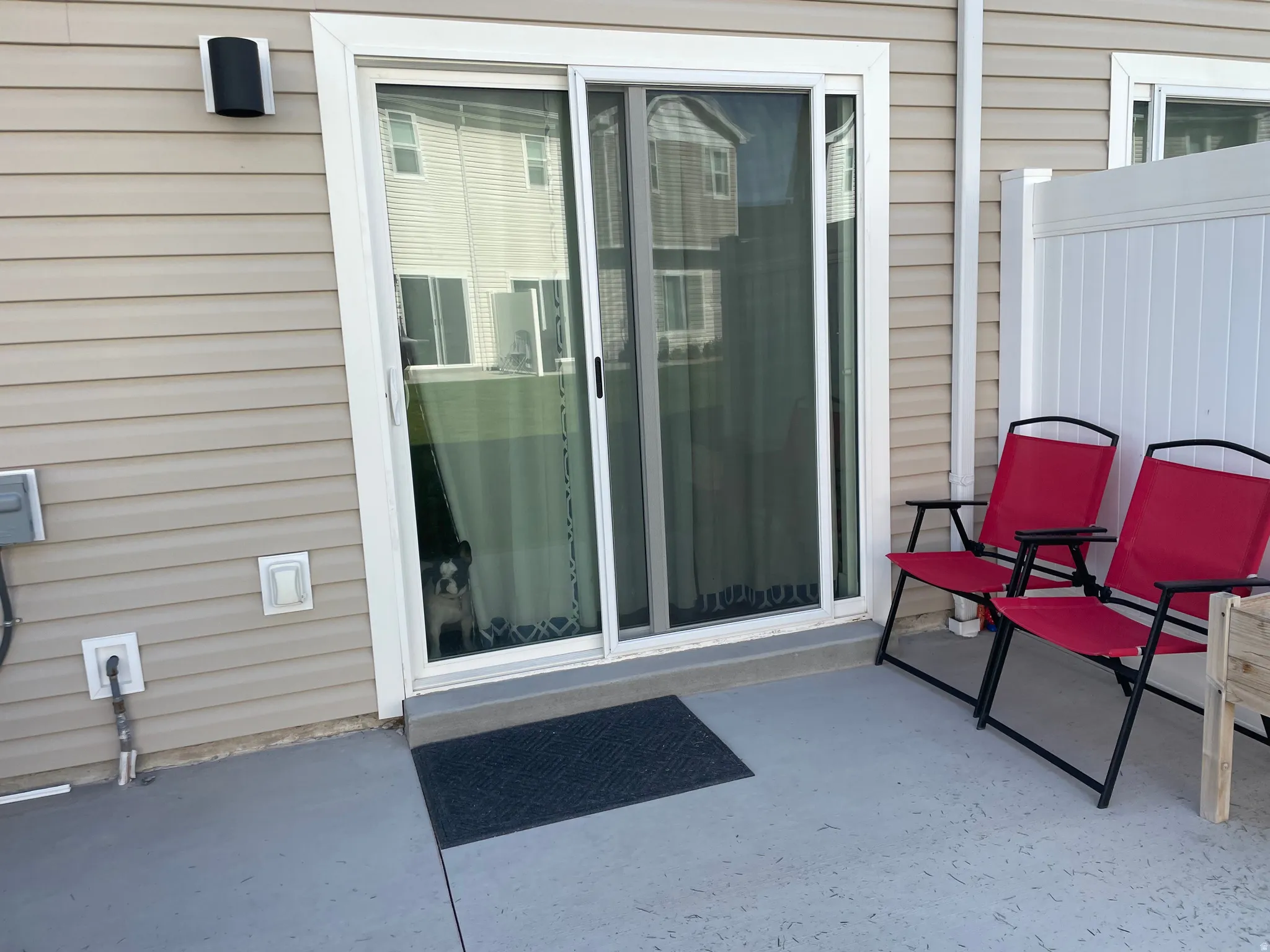 Outdoor patio with a sliding glass door, vinyl siding, and white privacy fencing