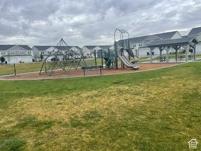 Community greenspace featuring a playground, climbing structure, and covered picnic area