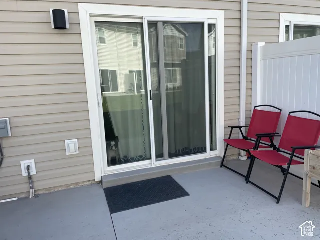 Outdoor patio with a sliding glass door, vinyl siding, and white privacy fencing