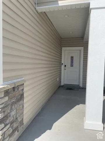 Entryway featuring horizontal siding, stone veneer accents, and a covered porch with recessed lighting