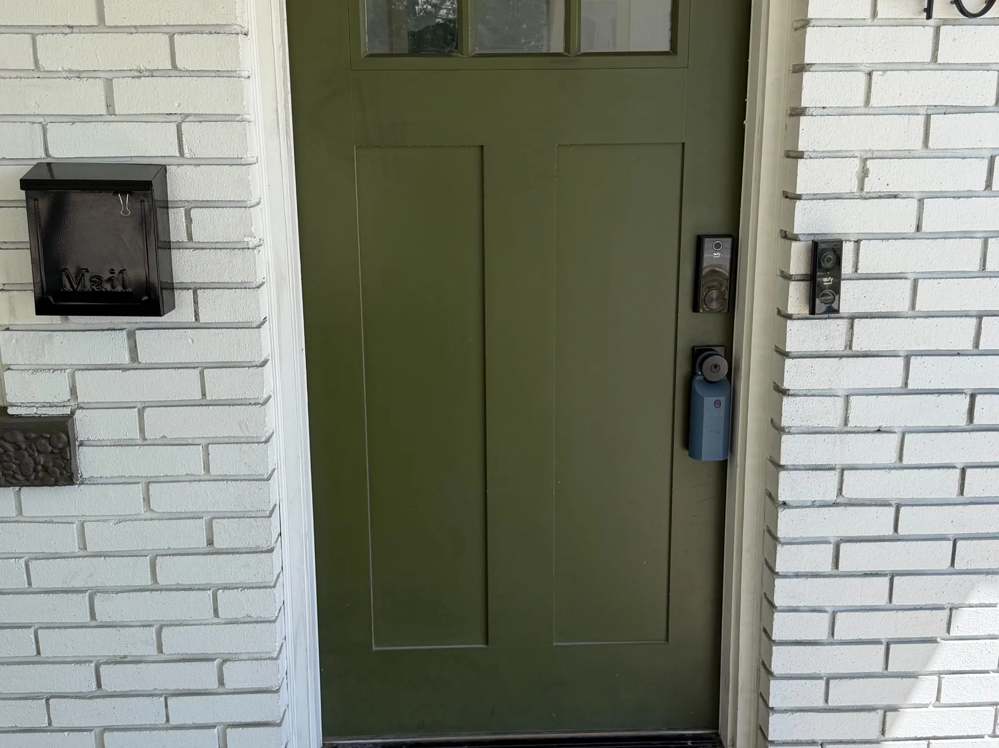White brick exterior with a green paneled door and transom windows