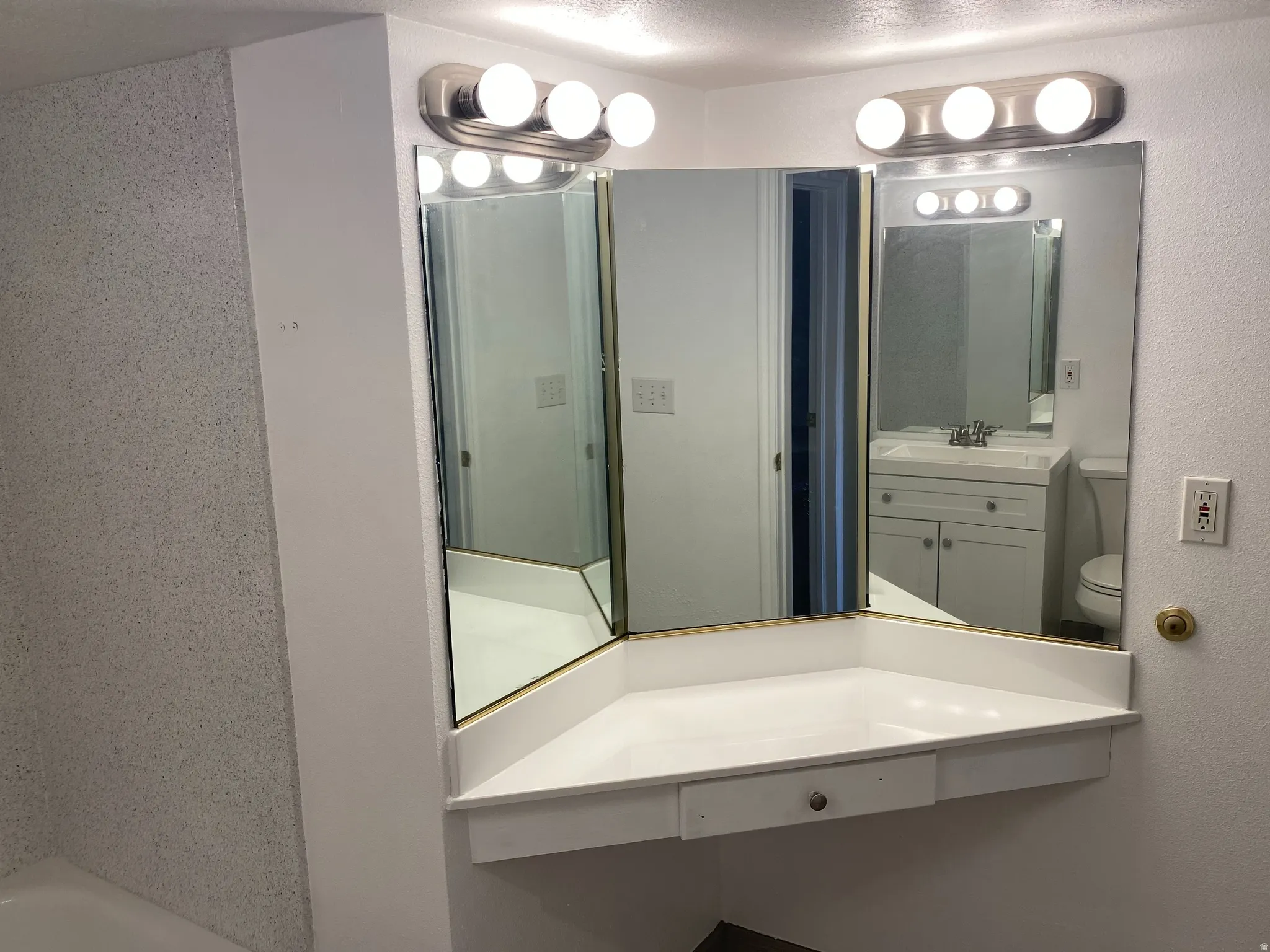 Vanity area featuring a three-panel mirror, built-in countertop, and integrated drawer