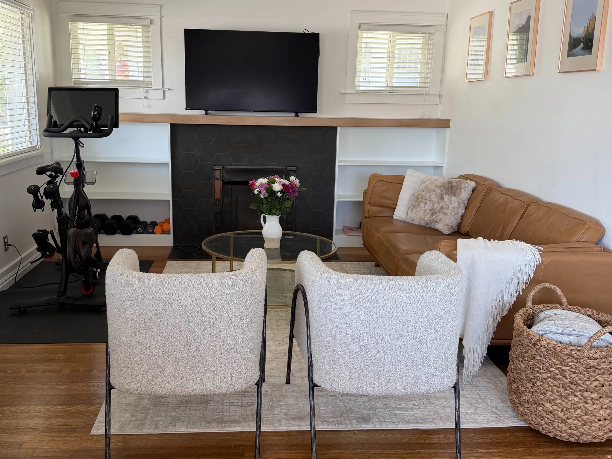 Hardwood flooring, fireplace with a dark surround, built-in shelving, and white baseboards