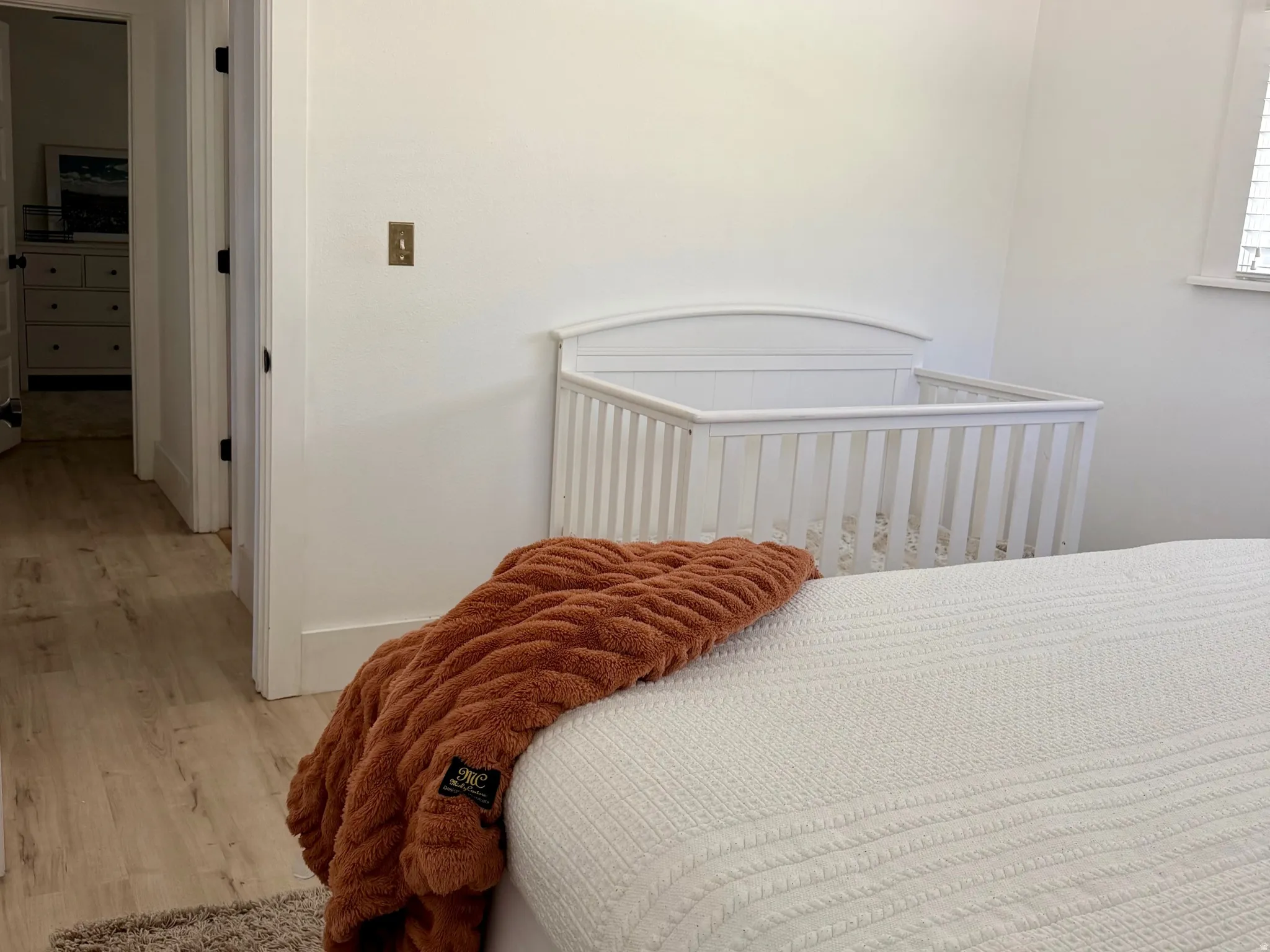 White walls, wood-finish flooring, ceiling fan with integrated lighting, and white trim throughout