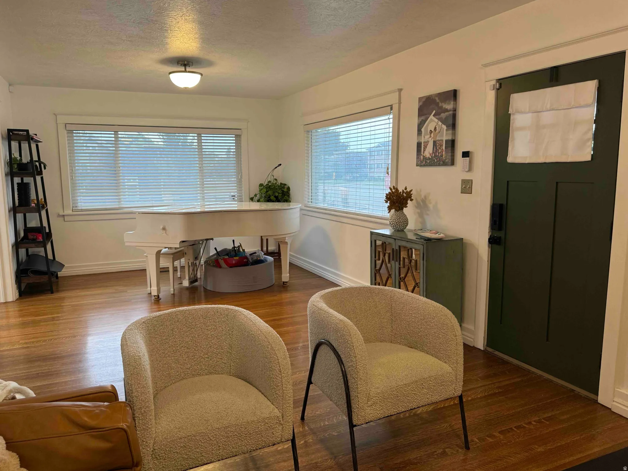 Hardwood flooring throughout, bright windows with blinds, built-in shelving, and a deep green entry door
