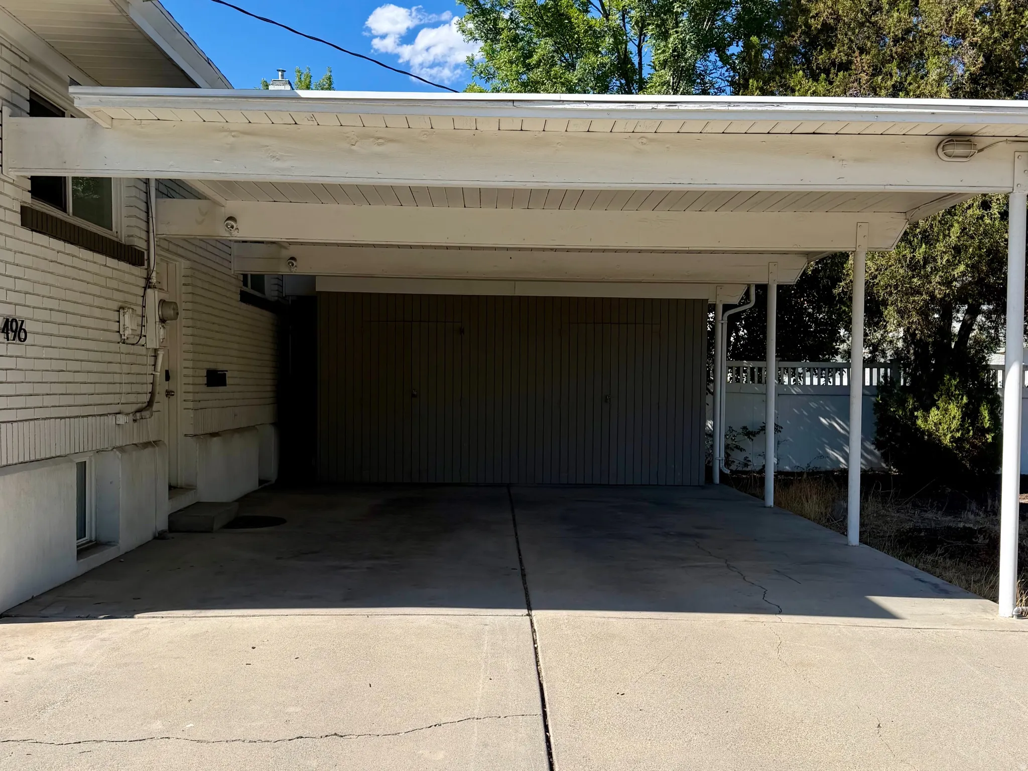 Carport structure with a flat roof, concrete driveway, and white siding