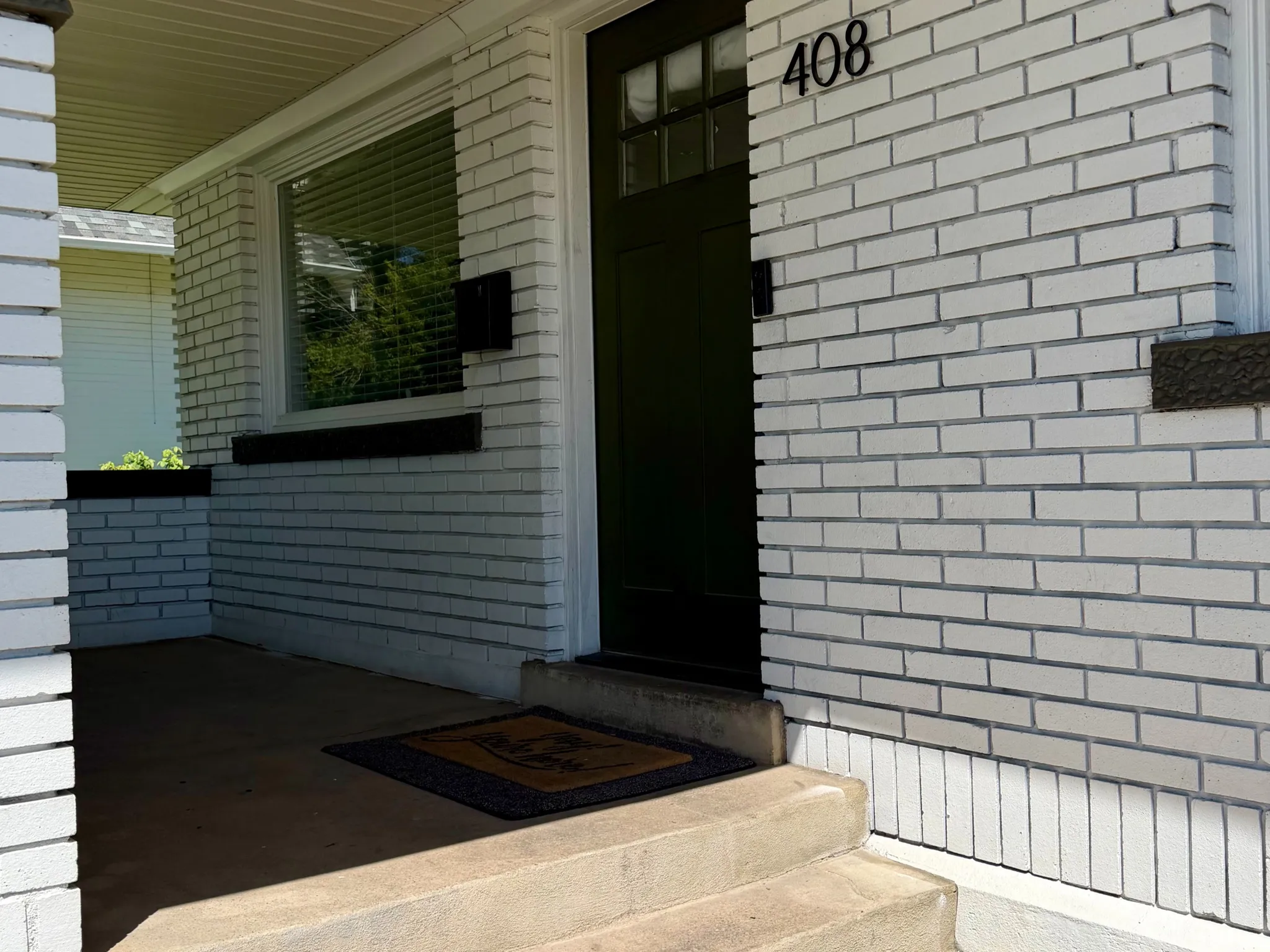 Brick exterior with contrasting dark trim, covered porch, and concrete steps