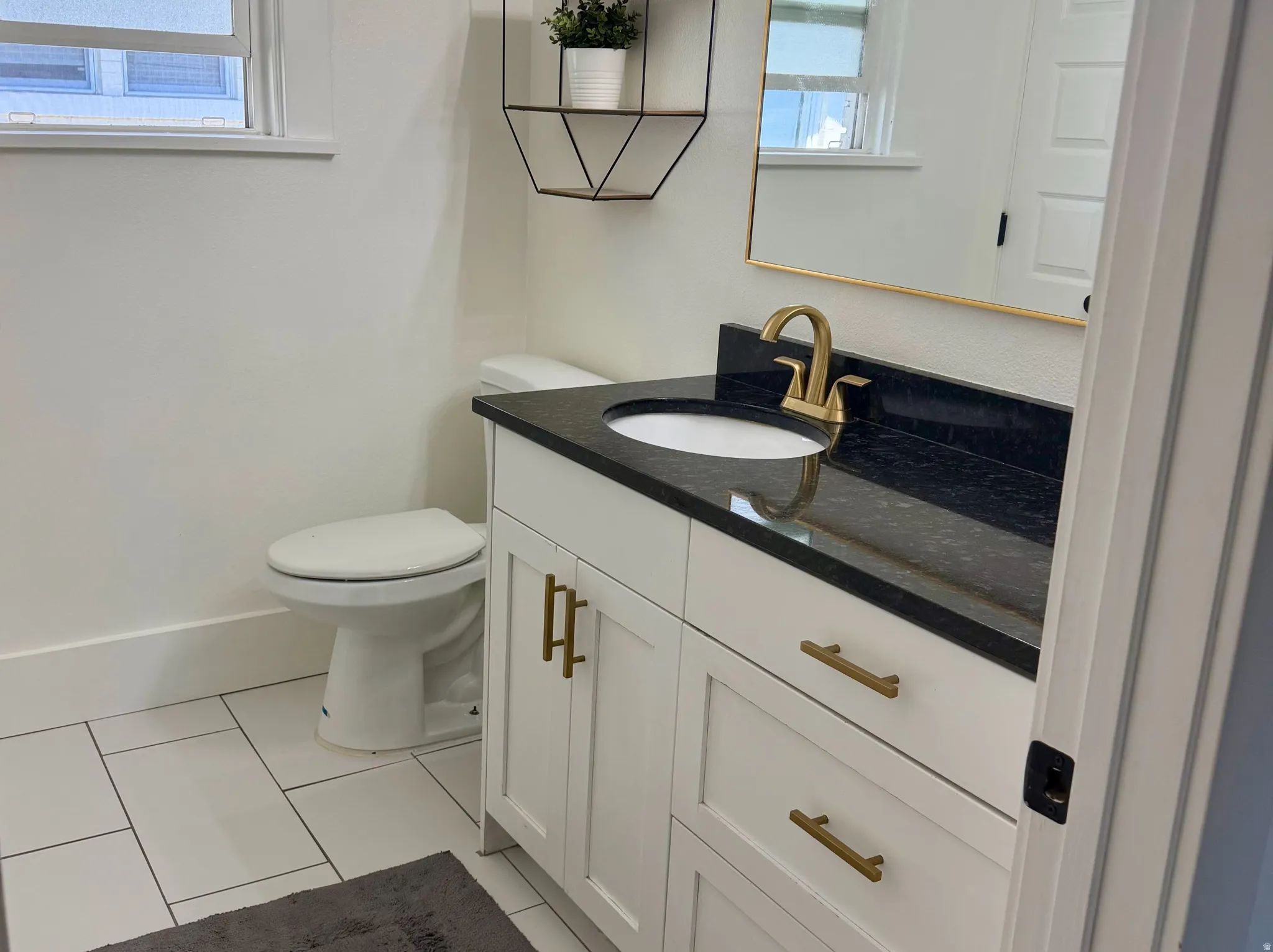 Modern bathroom featuring a white vanity with brass hardware, black countertop, and integrated sink