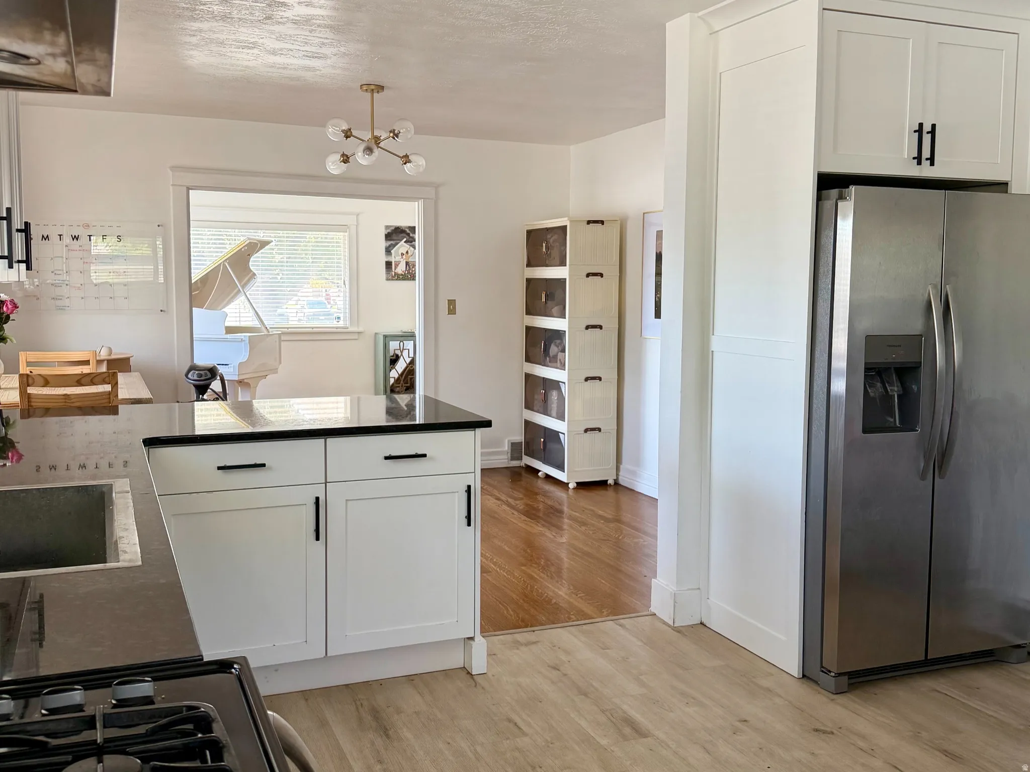 Kitchen featuring wood-finish flooring, white cabinetry with black hardware, dark countertops, and recessed lighting