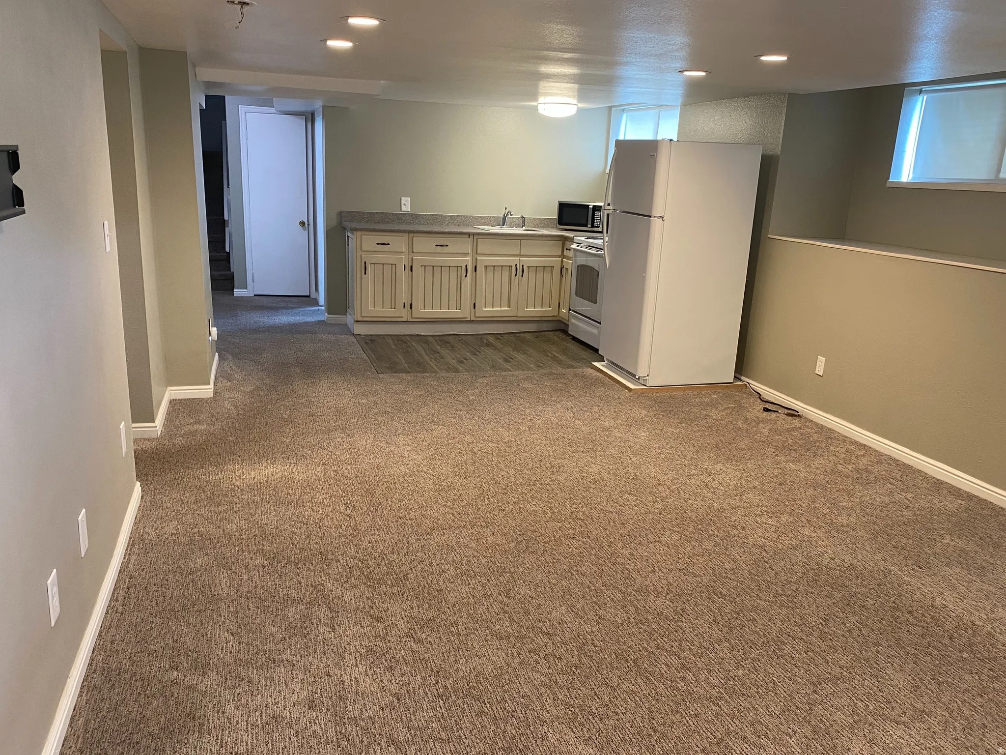 Open concept living space featuring recessed lighting, a built-in kitchenette with a sink, and a window