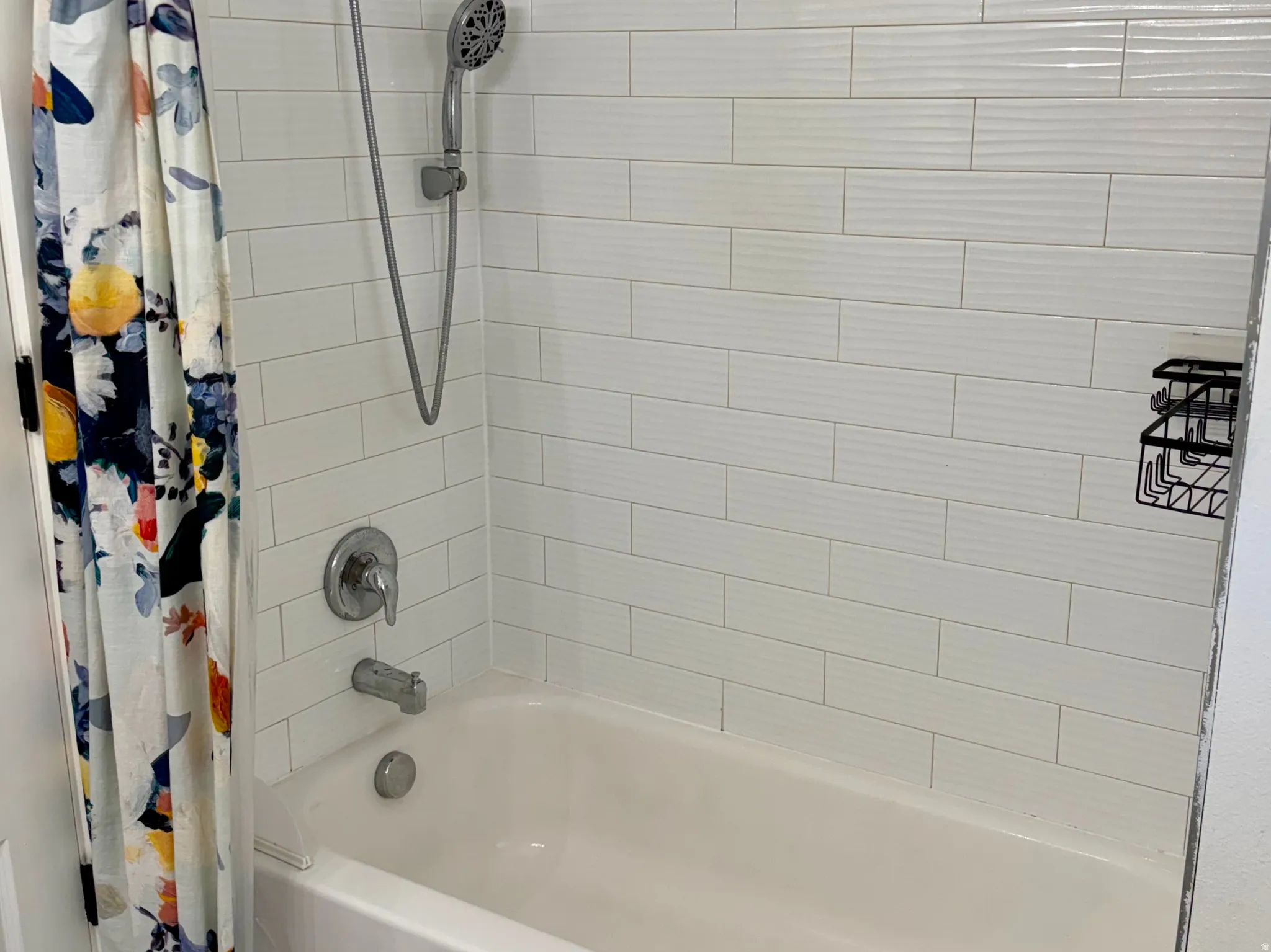 Bathtub with subway tile surround, mosaic tile accent, rainfall showerhead, and handheld shower sprayer