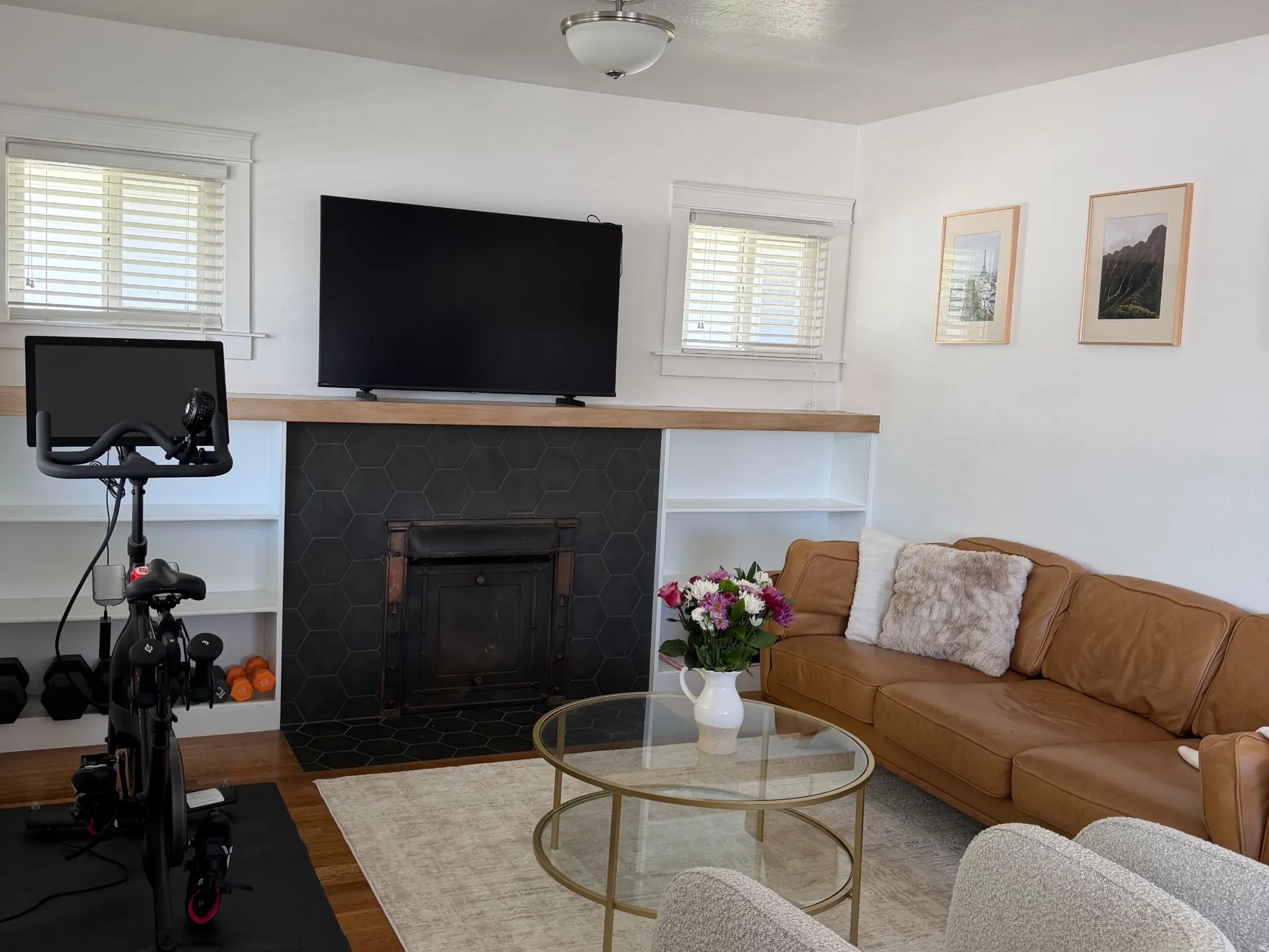 Wood-finish flooring, white walls, and a fireplace with a black hexagonal tile surround
