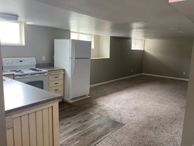 Kitchen area with white appliances, light-toned cabinetry, and dark countertops