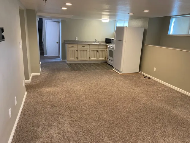 Open concept living space featuring recessed lighting, a built-in kitchenette with a sink, and a window