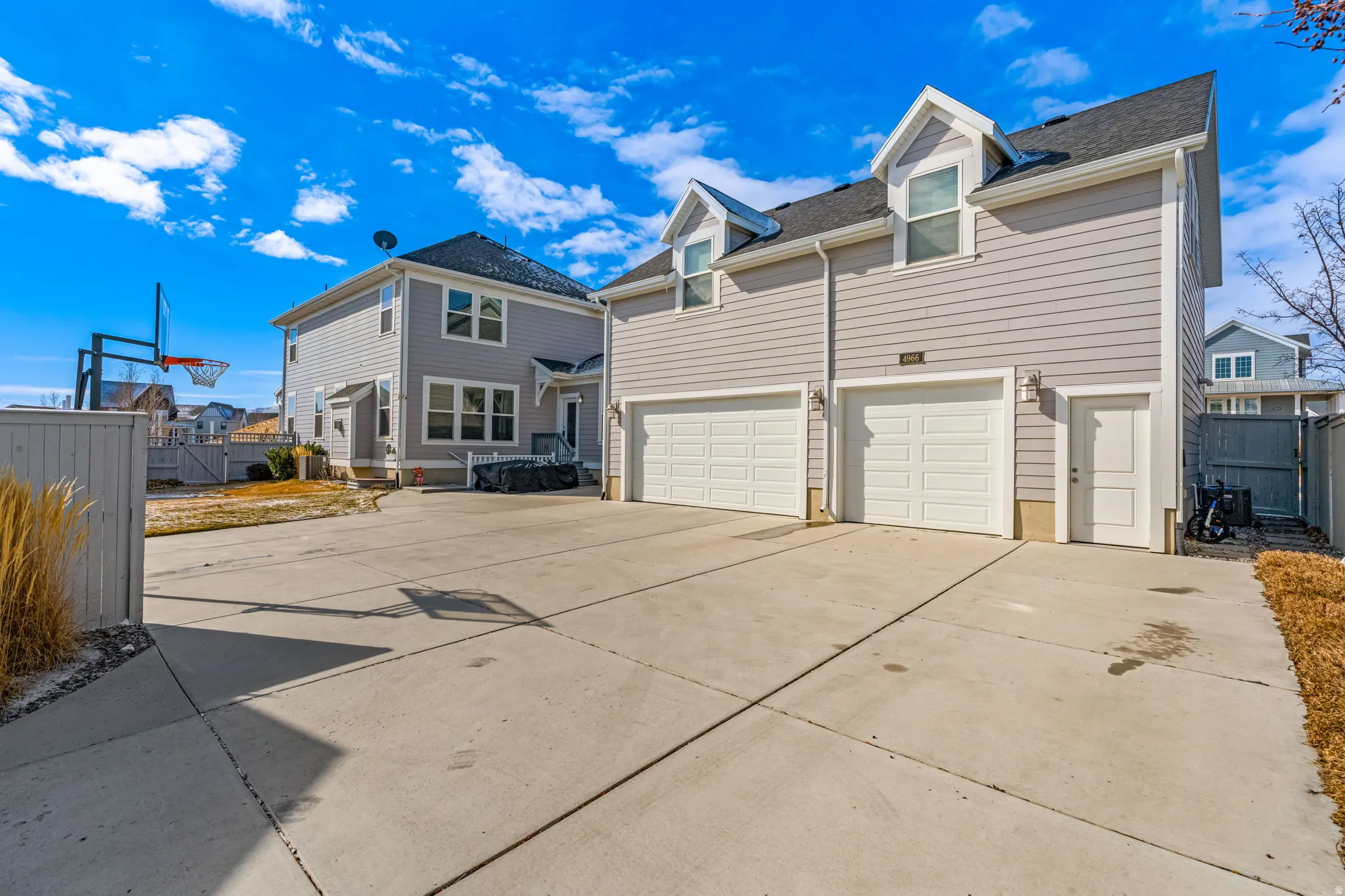 Expansive concrete driveway with a two-car garage featuring individual doors, and a separate utility door