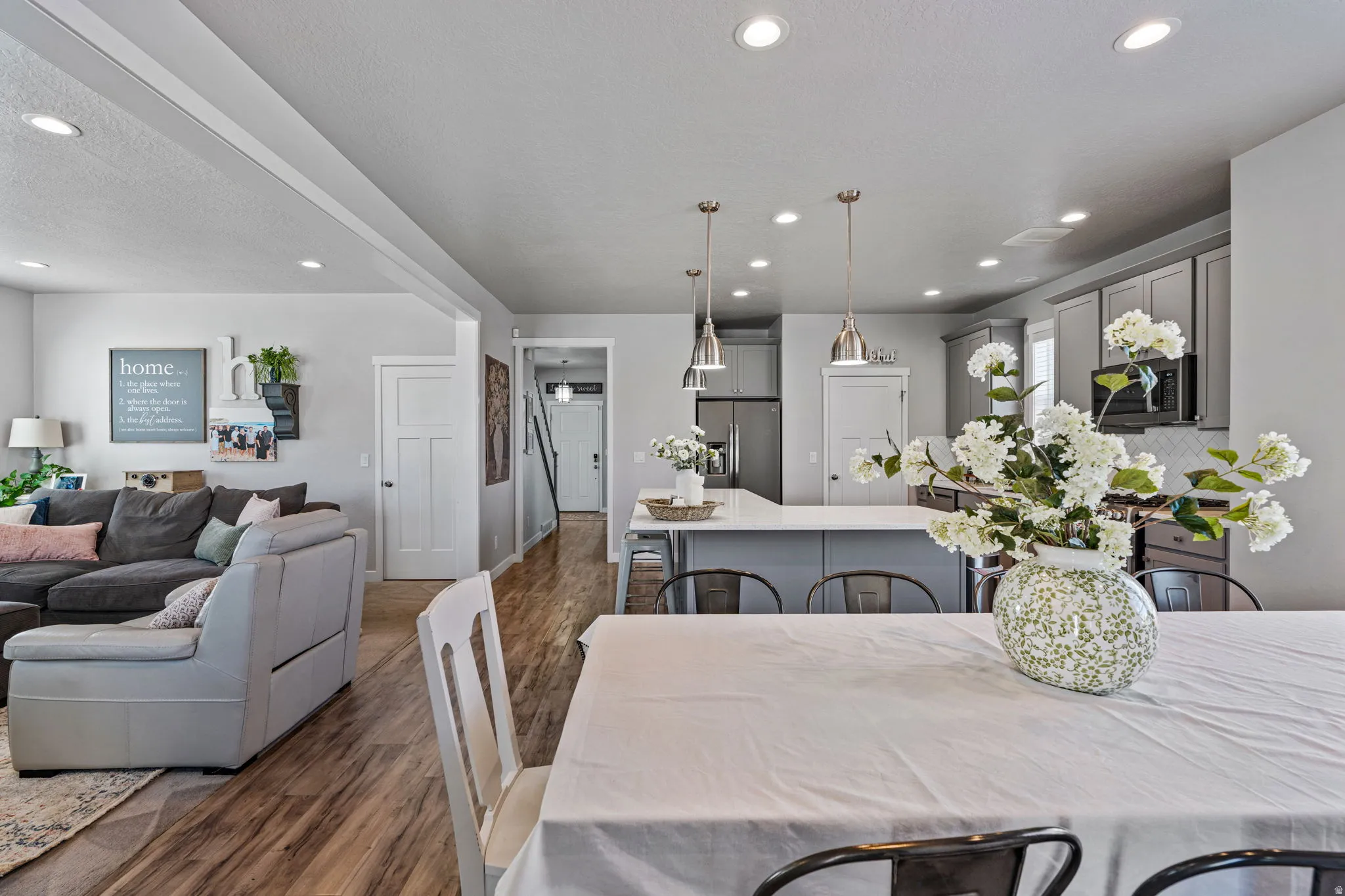 Recessed lighting, wood-finish flooring, and shaker-style cabinetry with pendant lighting