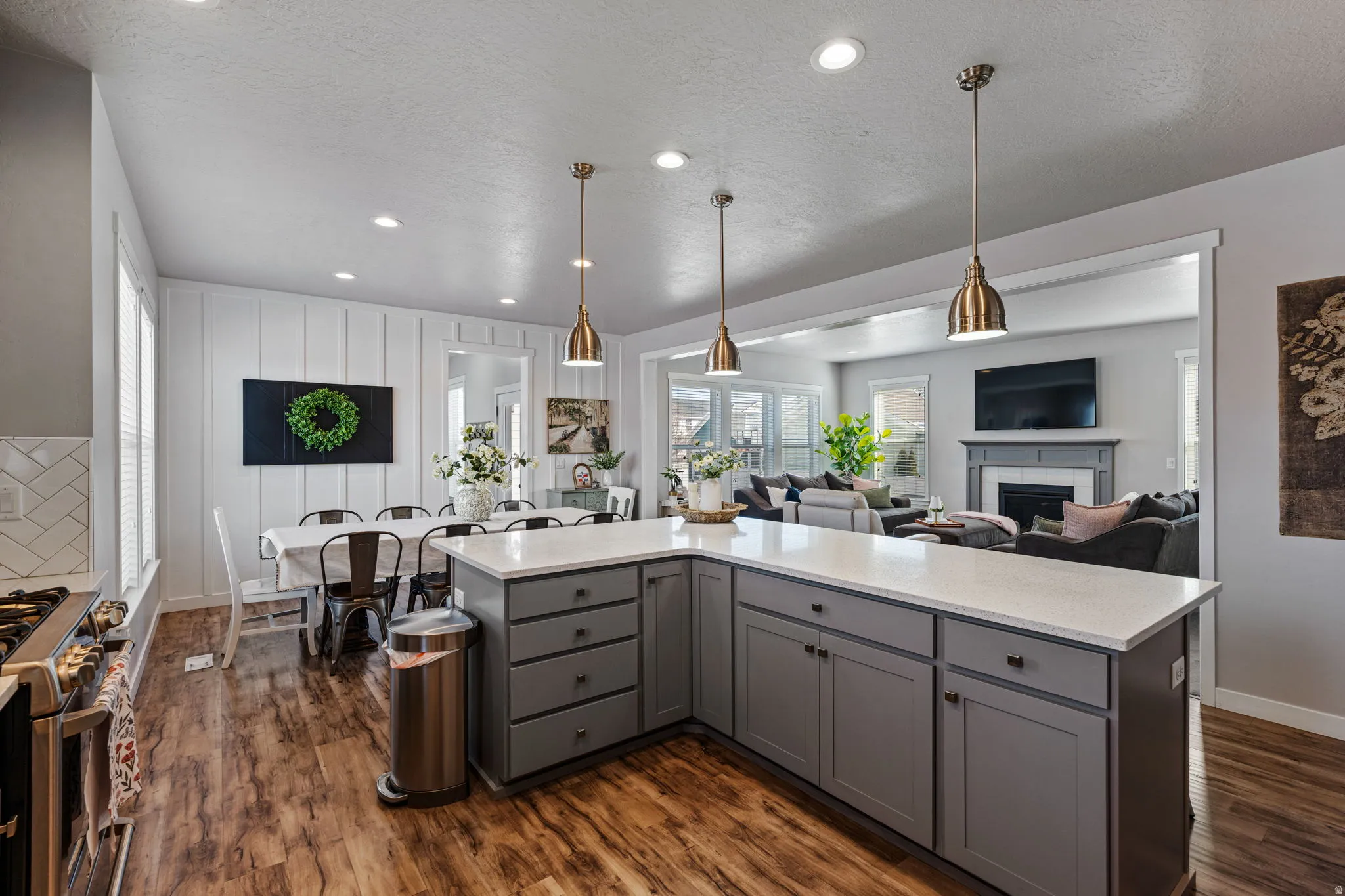 Kitchen island with light-toned countertop, wood-finish flooring, recessed lighting, and pendant fixtures