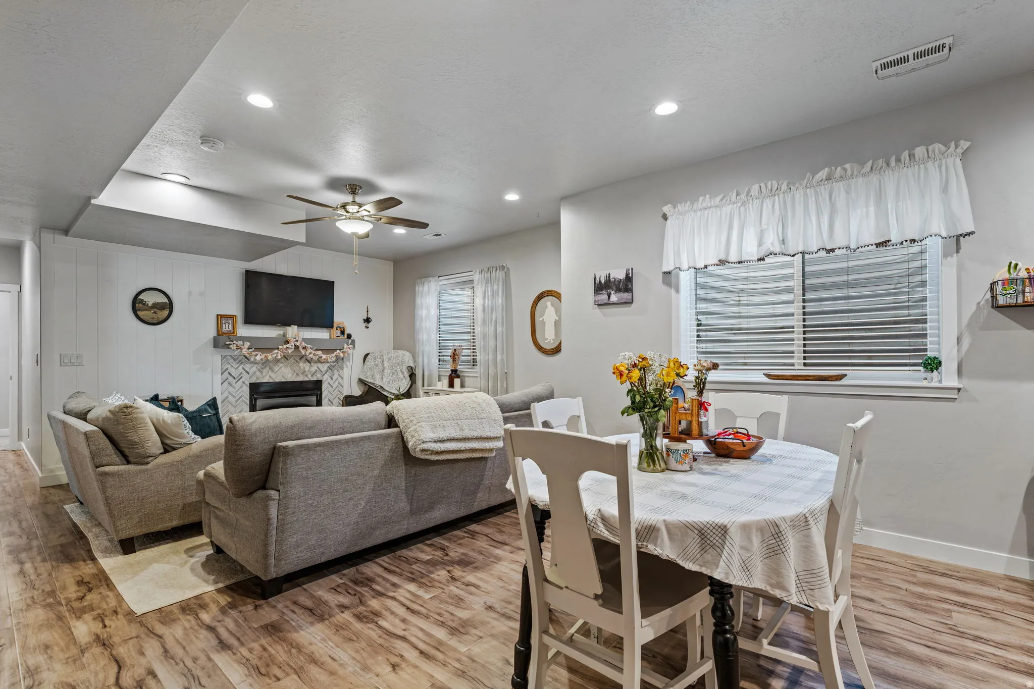 Wood-finish flooring throughout, featuring a fireplace with a herringbone tile surround and a wood mantel