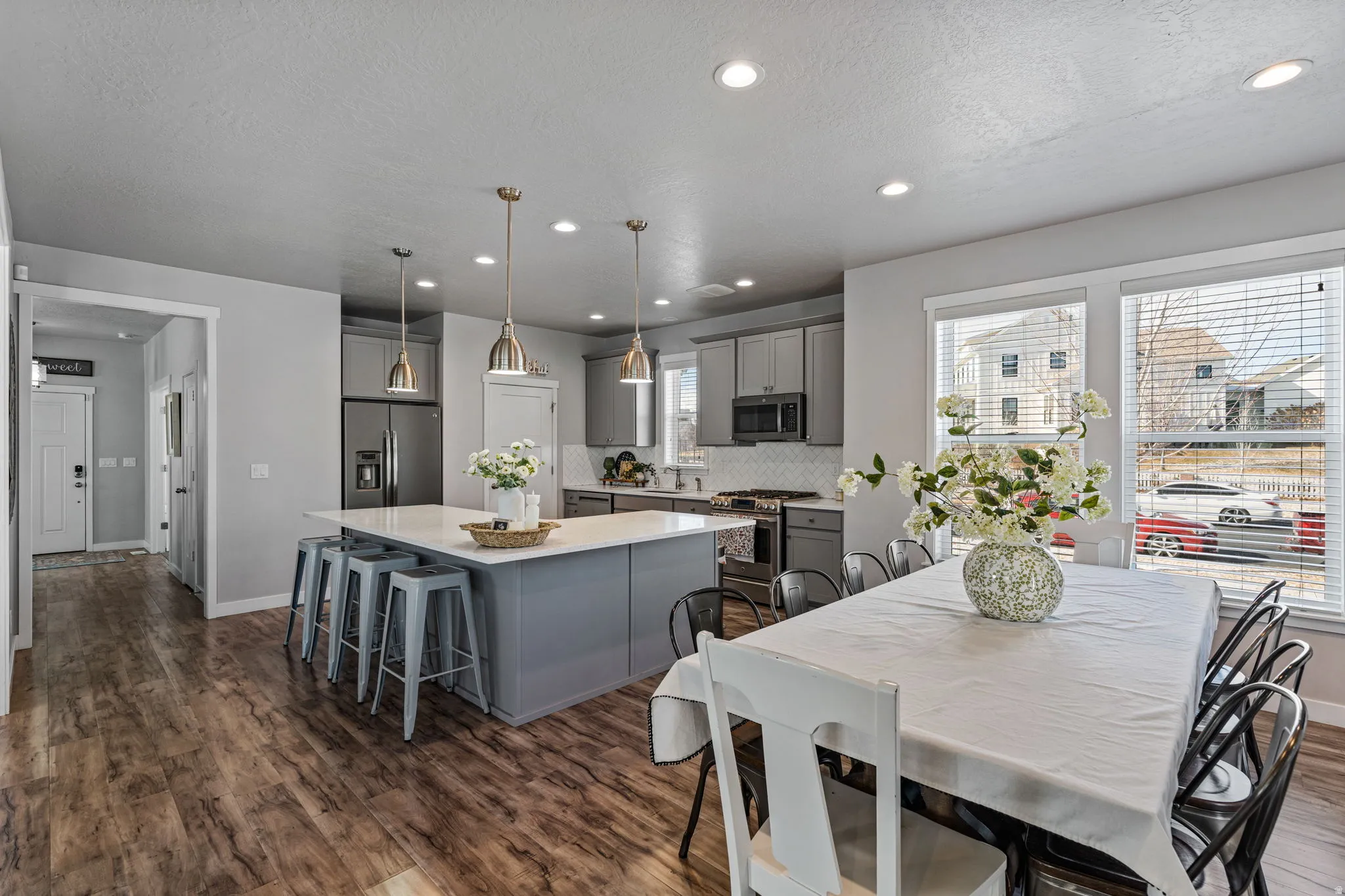 Open-concept kitchen and dining area featuring wood-finish flooring, recessed lighting, a kitchen island with pendant lights, and stainless steel appliances