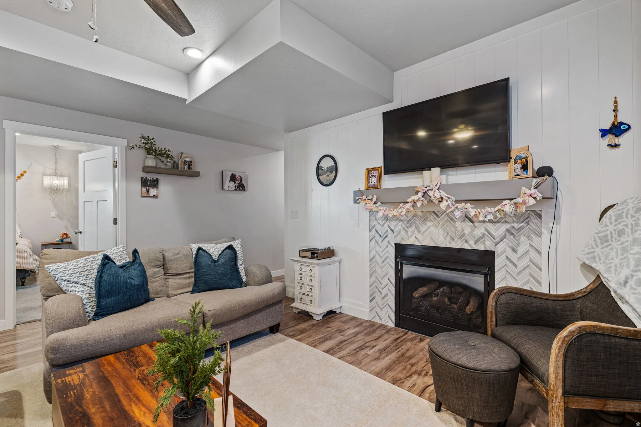 Fireplace with herringbone tile surround, wood-finish flooring, ceiling fan, and recessed lighting