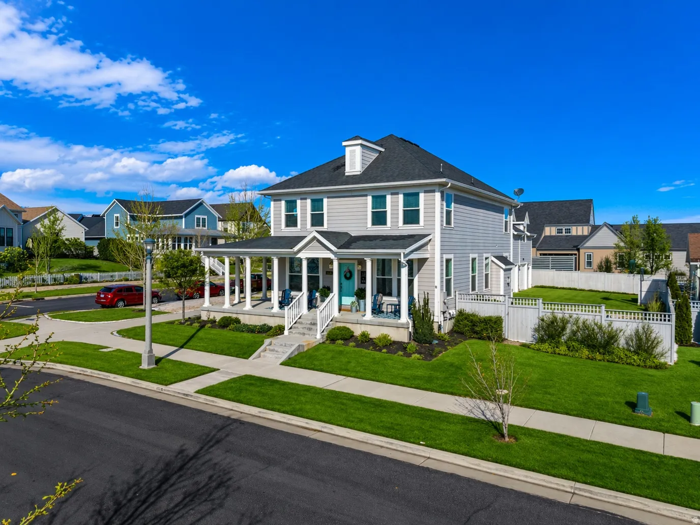 Charming Colonial-style residence showcasing a crisp white exterior with black gable roof, front-facing covered porch with white columns, and manicured landscaping