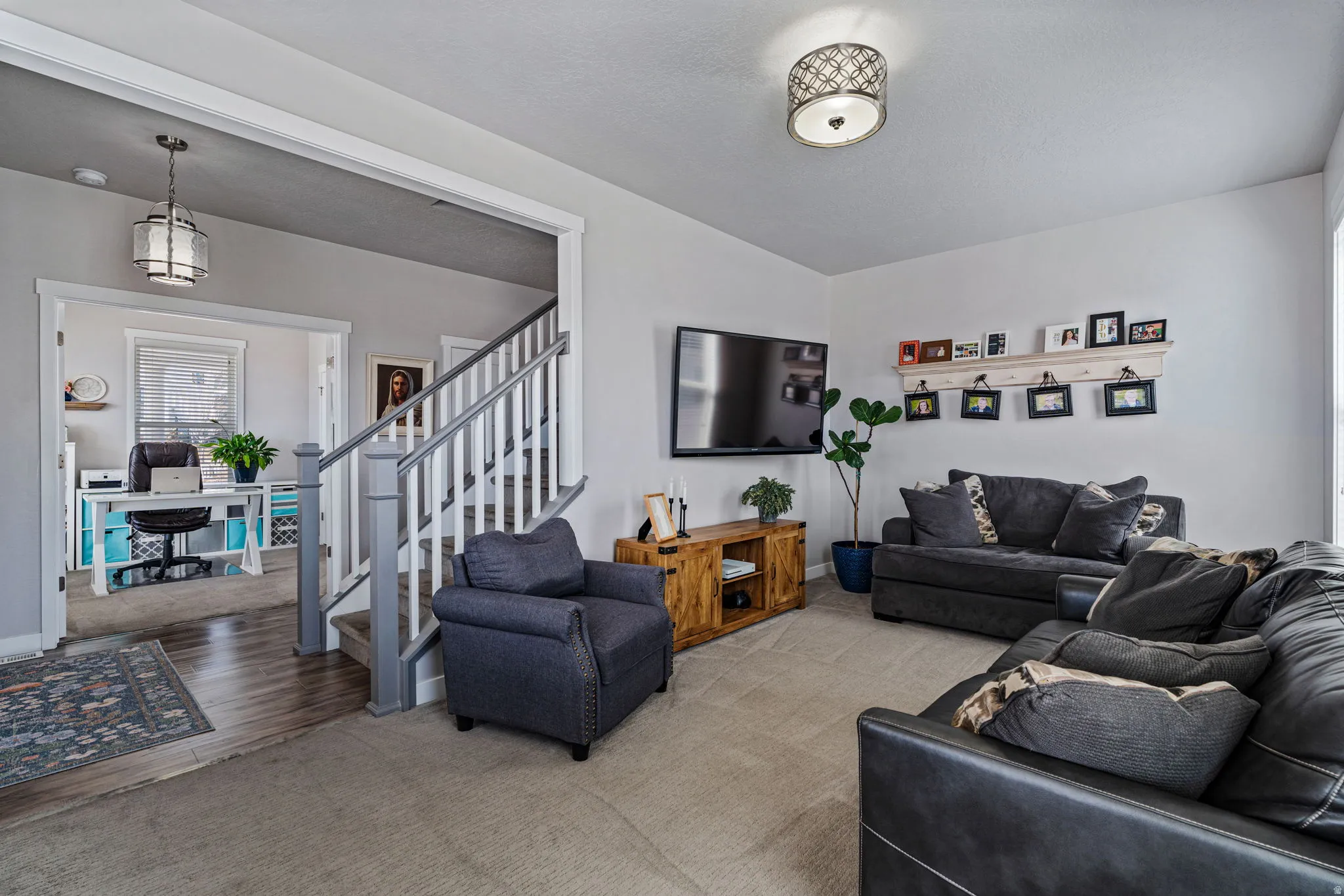Carpeted living area with white walls and a decorative flush mount light fixture