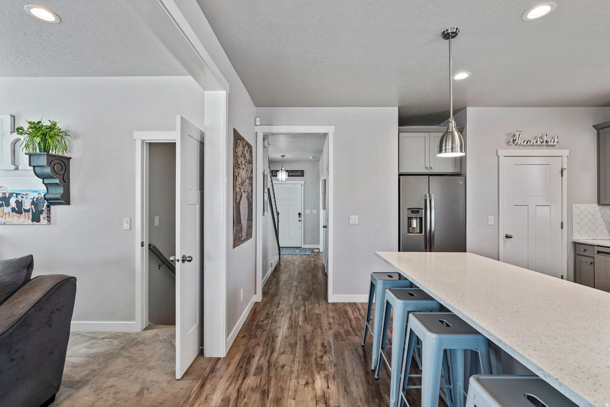 Open-concept layout featuring wood-finish flooring, recessed lighting, a kitchen island with stone countertop, and stainless steel appliances