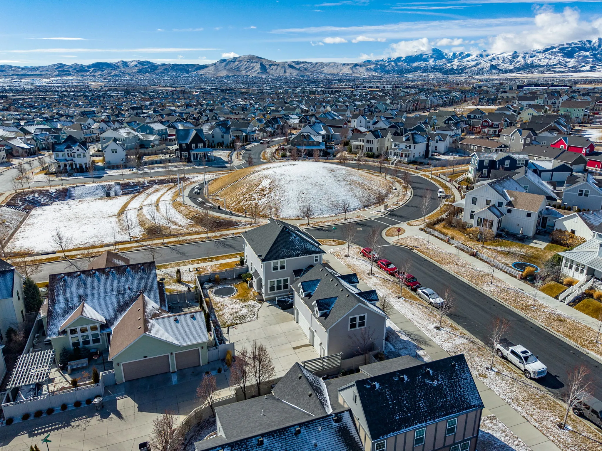 Residential neighborhood with a prominent central roundabout and distant snow-capped mountains