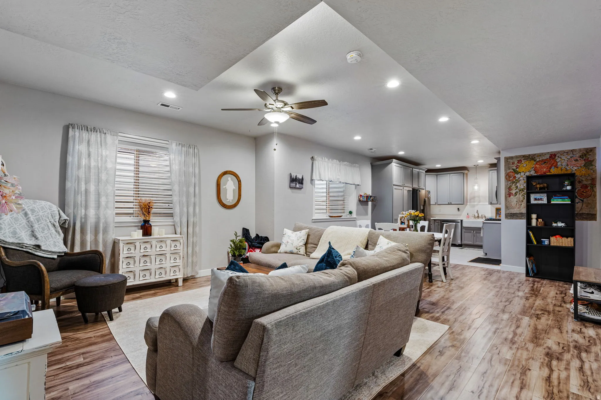 Recessed lighting, wood-finish flooring, ceiling fan, kitchen with gray cabinetry, and white window blinds