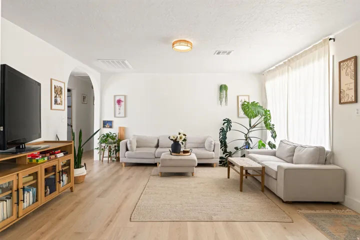 Light wood-finish flooring, white walls, and an arched doorway