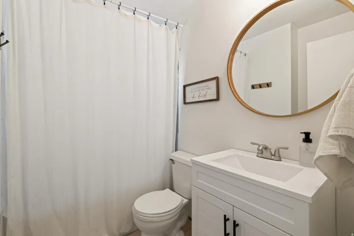 White vanity with shaker-style door fronts and matte black hardware, integrated white sink, and polished chrome faucet