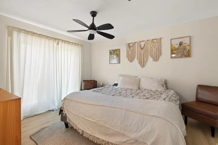Recessed ceiling with a black ceiling fan, light-toned walls, and wood-finish flooring