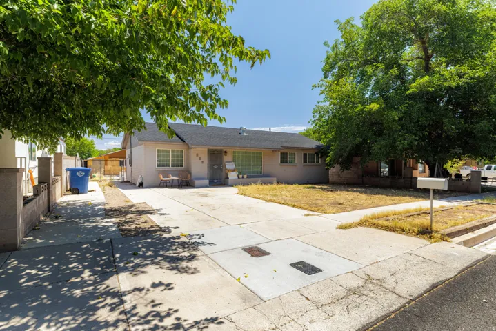 Single-story residence featuring a concrete driveway, mature trees, and a low-pitched roof